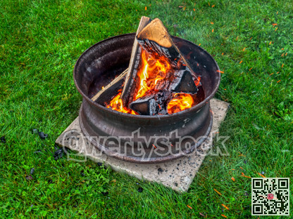 Campfire in a steel wheel on the concrete base and green lawn