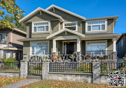 Modern residential house with big front yard behind stone and metal fence