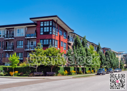 Red residential building on a street corner with cars parked beside