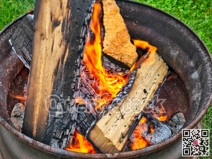 Campfire in a steel wheel on the concrete base and green lawn