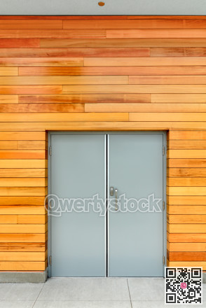 Double-swinging door in a building with wooden siding of the wall