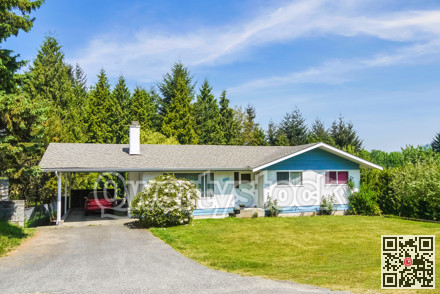 Modest residential house with big front yard and a car parked under carport