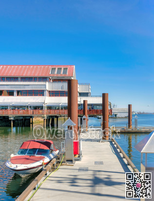 Motorized boat moored at the pier with seafood restaurant on the background