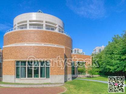 Green wall of trees and mowed lawn along the round shaped office building