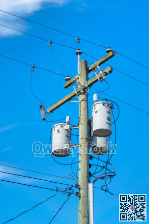 Wooden electricty pole with mounted transformators on blue sky background