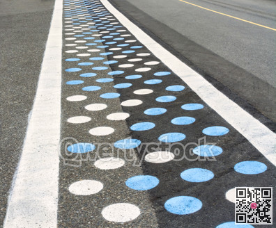 Pedestrian crosswalk on asphalt road colored with blue and white dots