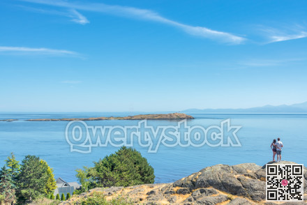 Young couple looking at Pacific ocean seascape from the rocky shore