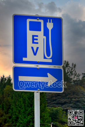 EV charging station road sign on dramatic sky background